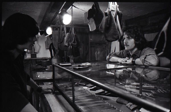 Don Muller with customer at the counter in the Leather Shed, ca. 1973